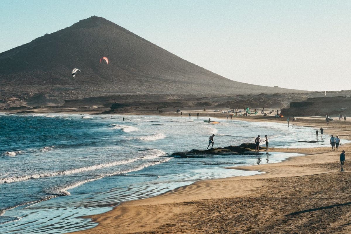 Kitesurfers and beachgoers at El Médano beneath Montaña Roja