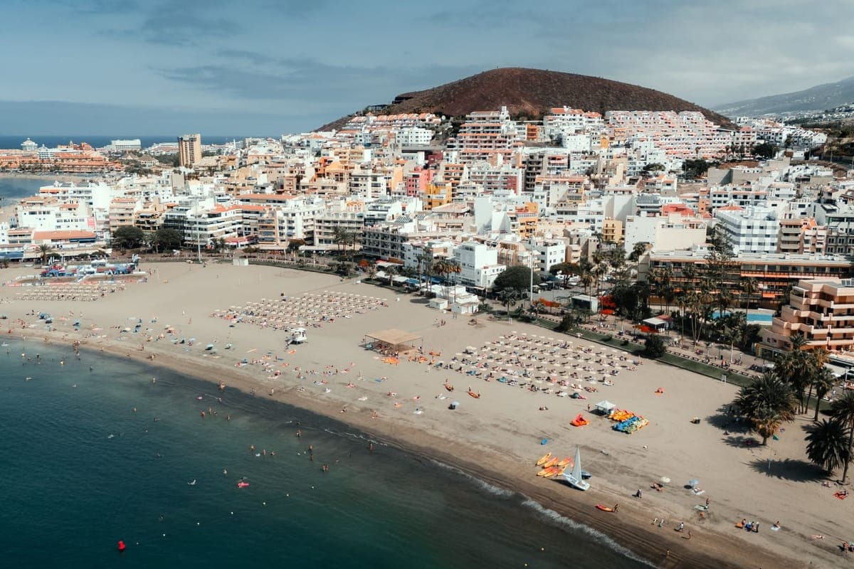 Aerial view of Los Cristianos beach and town with a volcanic hill behind