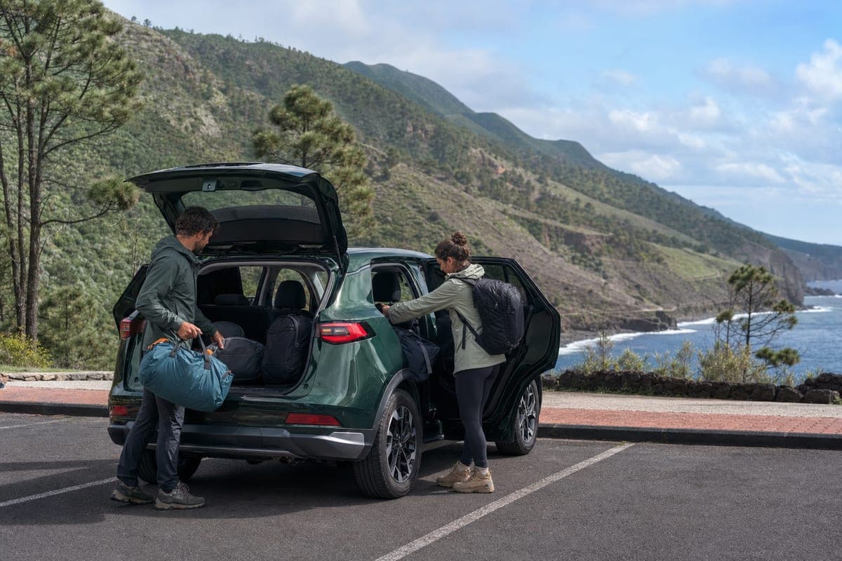 Hikers loading a rental car beside La Palma's green volcanic coast